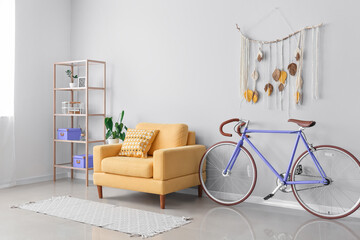 Stylish interior with bicycle, yellow armchair and shelf unit