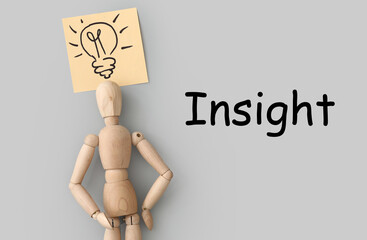Wooden mannequin with drawn light bulb and INSIGHT on grey background