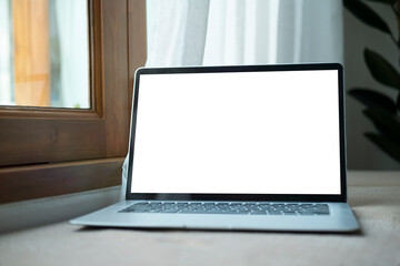 Fototapeta premium Mock up computer laptop with blank screen on wooden table at comfortable workplace.