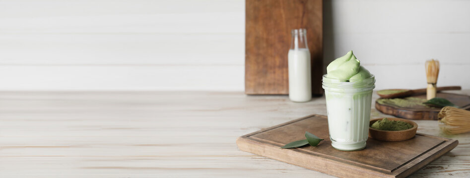 Glass of tasty dalgona matcha latte on wooden background with space for text