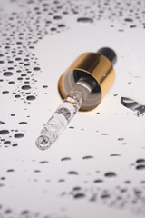 Fototapeta na wymiar A pipette of cosmetic gel on the background of drops.