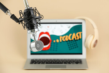 Stand with microphone and laptop with word PODCAST on color background, closeup