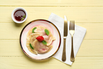 Plate with tasty strawberry dumplings and jam on color wooden background