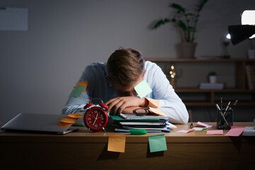 Sleeping young man with sticky notes in office at night