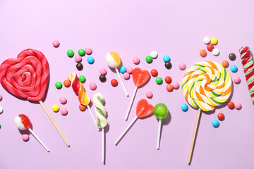 Different lollipops and candies on lilac background, closeup