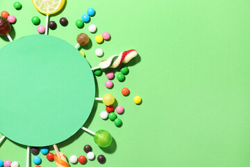 Composition with blank card, lollipops and candies on green background, closeup