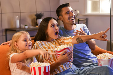 Emotional family with popcorn watching movie at home in evening
