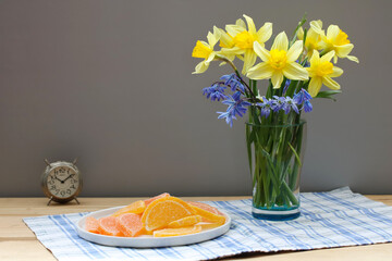 bouquet of yellow daffodils and marmalade on the table.