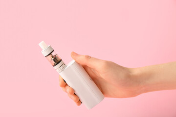 Female hand with modern vape mod on pink background