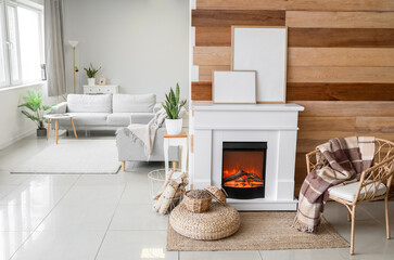 Interior of modern living room with mantelpiece, firewood and frames