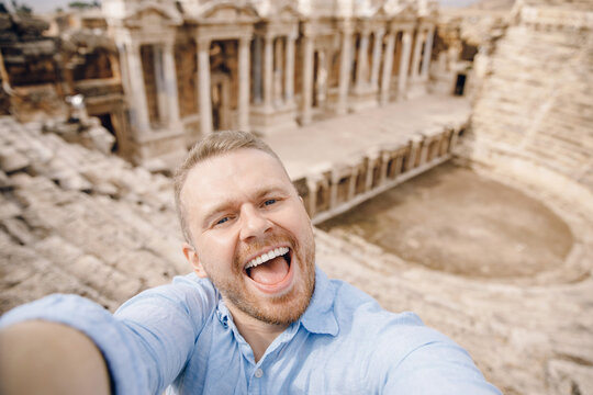 Tourist man taking selfie photo on background Amphitheater in Hierapolis ancient city Pamukkale Turkey