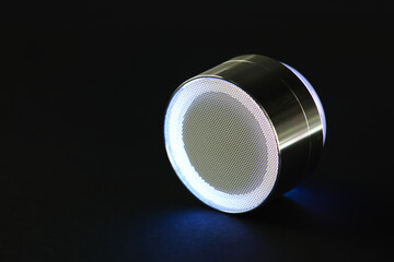 Glowing wireless portable speaker on black background