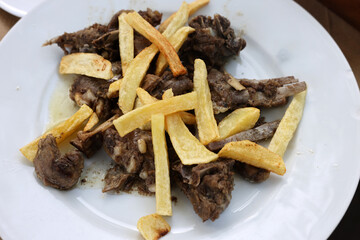 grilled goat with fries on a white plate