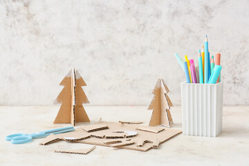 Handmade cardboard trees and stationery supplies on light background