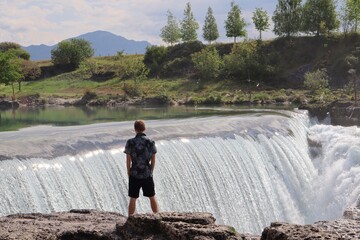 Chłopak stojący tyłem na tle wodospadu Niagara w Czarnogórze - obrazy, fototapety, plakaty