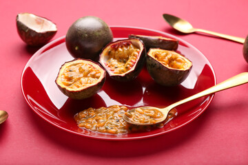 Plate with delicious cut  passion fruits on red background