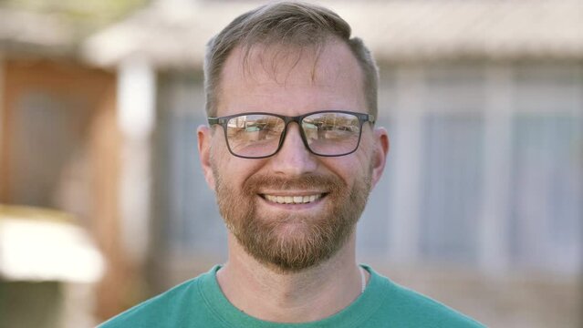 Portrait of a young happy businessman looking at the camera. professional male teacher, smiling bearded entrepreneur or manager posing outdoors, face closeup