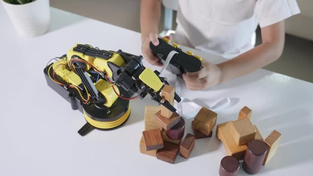 Happy Asian little boy using remote control playing robotic machine arm for pick up wood block, Funny learning successful getting a lesson control robot arm, Technology science education concept