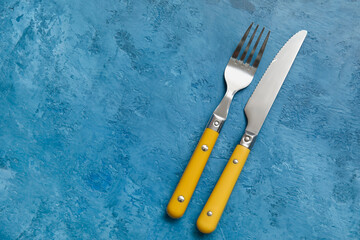Silver knife and fork on blue background