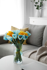 Vase with bouquet of beautiful tulips in colors of Ukrainian flag  on table in living room