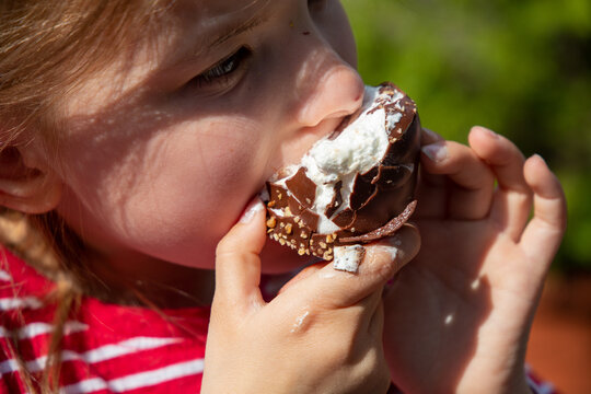 Siebenjähriges Mädchen isst einen Schokokuss auf einem Volksfest (model released)