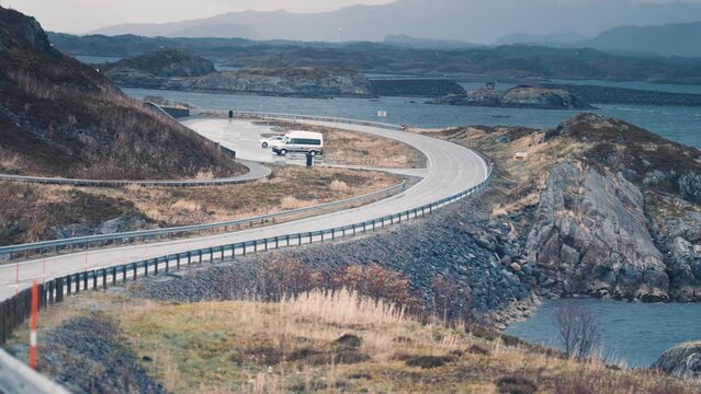 Lyngholmen parking on the Atlantic road. Campers and cars parked on the lot. Road winds through the archipelago. Slow-motion, pan forward.
