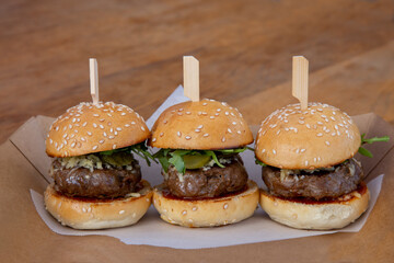 mini burger sliders on a wooden board up close low light with grain and out of focus