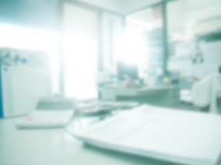 Blur in office inside background.over light on defocus  interior room workplace with calculator and document on table work space. business and finance backdrop concept.