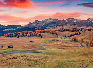 Unbelievable autumn sunrise in Alpe di Siusi village with winding country road. Colorful morning scene of Dolomite Alps, Ortisei locattion, Italy, Europe. Traveling concept background..