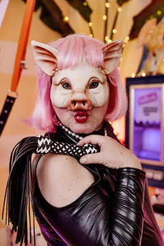 Man wearing pig mask holding whip