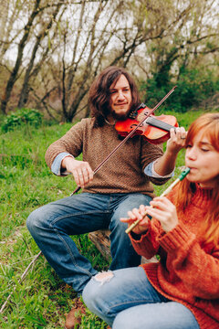 Man and woman rehearsing with musical instruments in field
