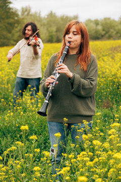 Man and woman practicing musical instruments in flower field