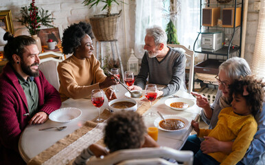 Fototapeta na wymiar Happy multiethnic multigeneration family having fun together around kitchen table.