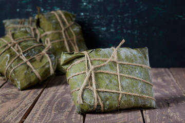 Tamales on a wooden table and green background. The Tamal is a typical and traditional food of Colombia.
