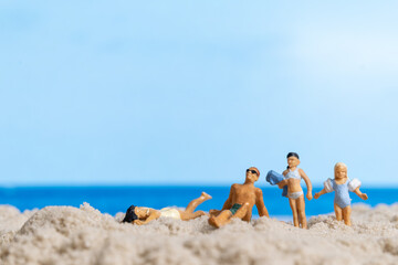 Fototapeta na wymiar Miniature people Happy family relaxing on The beach, Summer time concept