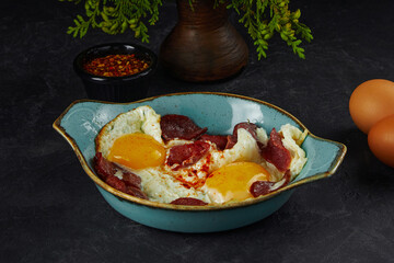 Sunny side up eggs with sausages in blue plate on table