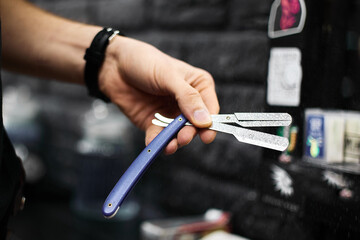 Man shows multitool with scissors and razor in barbershop
