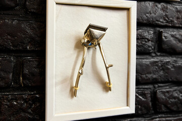 Vintage hair clippers in frame hang on black brick wall