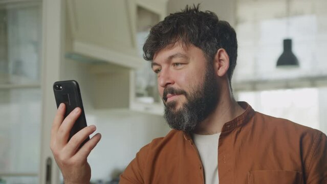 Close up of a. young adult caucasian man on a video conference call using his smart phone indoors
