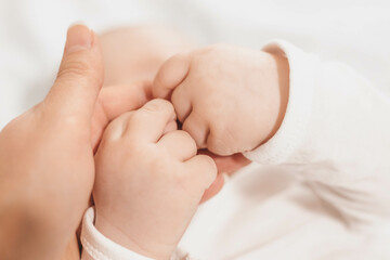 baby's hands holding mother's hand. The emotional bond between mother and child. Development of...