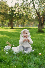 Easter Bunny baby boy. Egg hunting. Cute child in hat with ears and eggs on grass