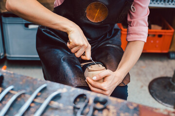 Shoemaker working on the frame of a shoe with lots of tools on the workbench