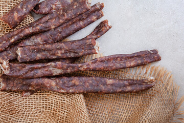 South African Dry Wors, a dried and cured sausage snack on grey, with copy space

