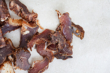 South African Biltong, a dried and cured meat sliced and on grey backdrop with copy space