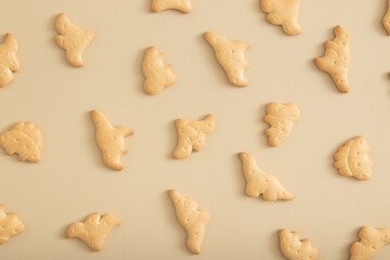 Cookies pattern in the form of dinosaurs top view on a beige background. Monochrome photo