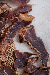 South African Biltong, a dried and cured meat sliced and on grey backdrop with copy space