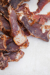 South African Biltong, a dried and cured meat sliced and on grey backdrop with copy space