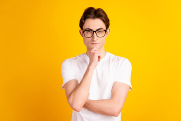 Photo of young guy arm touch chin thoughtful idea plan manager isolated over yellow color background