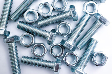 Top view on scattered bolts and nuts on white background