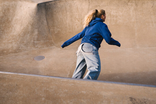 Teenage girl skateboarding in skatepark